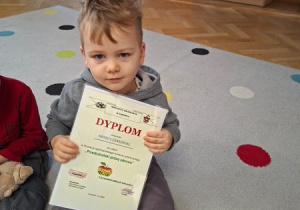 Henio prezentuje dyplom za udział w konkursie plastycznym