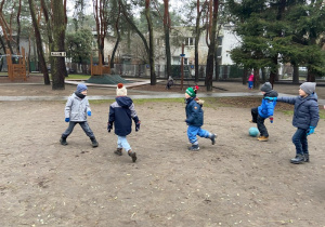 Piątka dzieci gra w piłkę nożną na boisku przedszkolnym
