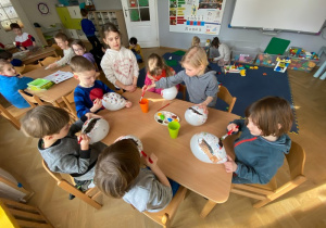 Dzieci przy stoliku malują farbami maski greckie