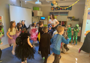 Dzieci tańczą w strojach z animatorką