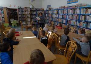 Dzieci w bibliotece słuchają odczytywanych wiadomości dotyczących sztuki