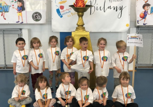 Zdjęcie grupowe dzieci z medalami i wygraną statuetką w ramach udziału w VI Bielańskiej Olimpiadzie Sportowej Przedszkolaków