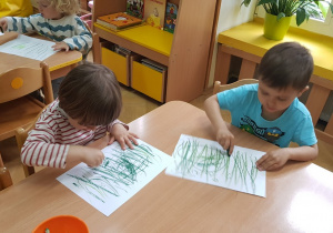 Dzieci rysują trawę na kartce papieru