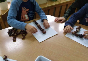 Dzieci ćwiczą cyfry z materiałów przyrodniczych